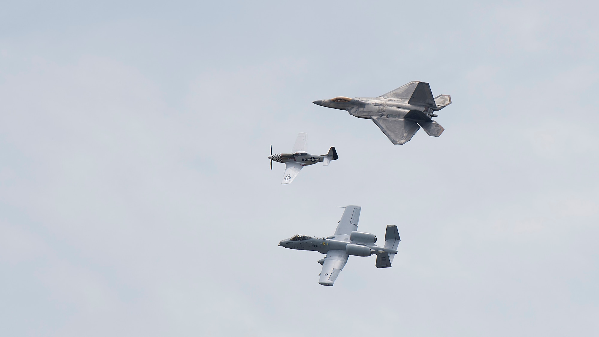 An A-10 Thunderbolt II (bottom), a P-51 Mustang (middle), and an F-22A Raptor (top), fly in formation during Tampa Bay AirFest 2018 hosted at MacDill Air Force Base, Fla., May 12-13, 2018. This heritage flight program presents the evolution of U.S. Air Force air power by flying today’s fighter aircraft next to vintage fighter aircraft.