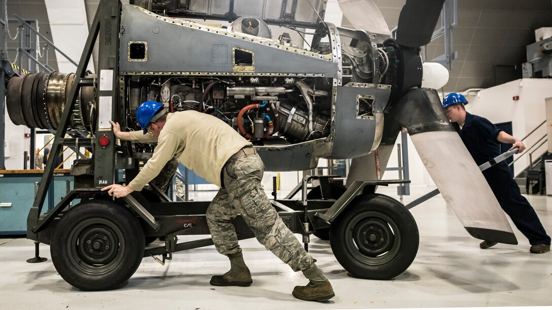 Airmen push an engine into place.