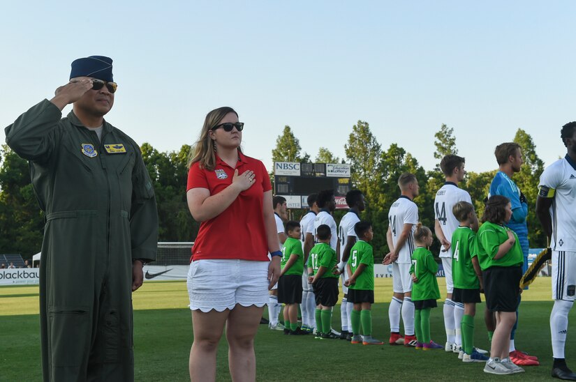 Col. Jimmy Canlas, left, 437th Airlift Wing commander, renders a salute during the national anthem while at the Charleston Battery Military Appreciation Night at the MUSC Health Stadium on Daniel Island in Charleston, S.C., May 12, 2018. Members of the 628th Civil Engineer Squadron Explosive Ordnance Disposal Flight also attended the game, showing attendees the equipment they work with and talking about what they do as members of EOD.