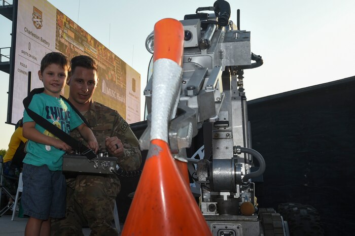 Staff Sgt. Matthew Koser, right, 628th Civil Engineer Squadron Explosive Ordnance Disposal Flight technician, shows four-year-old Jack Plett how to operate one of the EOD robots by clamping onto a traffic cone during the Charleston Battery Military Appreciation Night game at the MUSC Health Stadium on Daniel Island in Charleston, S.C., May 12, 2018. The military appreciation night allowed all military members to attend the soccer game for free. The Charleston Battery won against Bethlehem Steel 2-1.