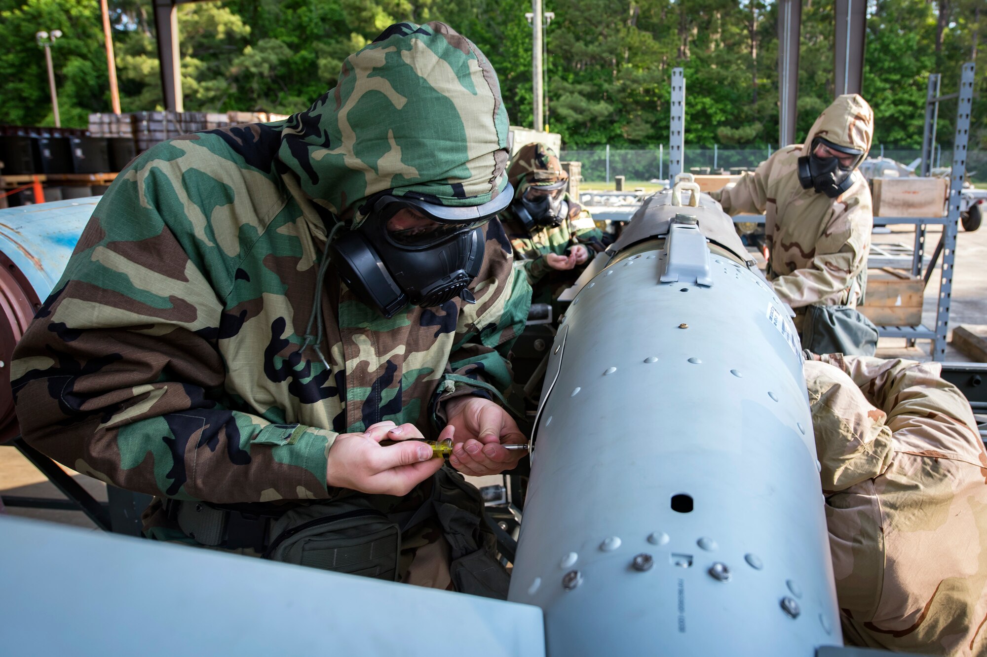 Airmen from the 23d Maintenance Squadron attach components to a Joint-Direct Attack Munition (JDAM) during a bomb building course, May 10, 2018, at Moody Air Force Base, Ga. To ensure readiness to complete their mission efficiently, Airmen practiced constructing a JDAM while wearing Mission Oriented Protective Posture gear to further simulate what their mission could entail.   (U.S. Air Force photo by Airman 1st Class Eugene Oliver)