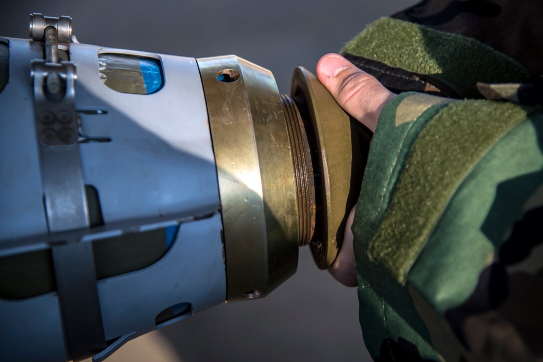 An Airman from the 23d Maintenance Squadron attaches a nose cone to a Joint Direct Attack Munition (JDAM) during a bomb building course, May 10, 2018, at Moody Air Force Base, Ga. To ensure readiness to complete their mission efficiently, Airmen practiced constructing a JDAM while wearing Mission Oriented Protective Posture gear to further simulate what their mission could entail. (U.S. Air Force photo by Airman 1st Class Eugene Oliver)