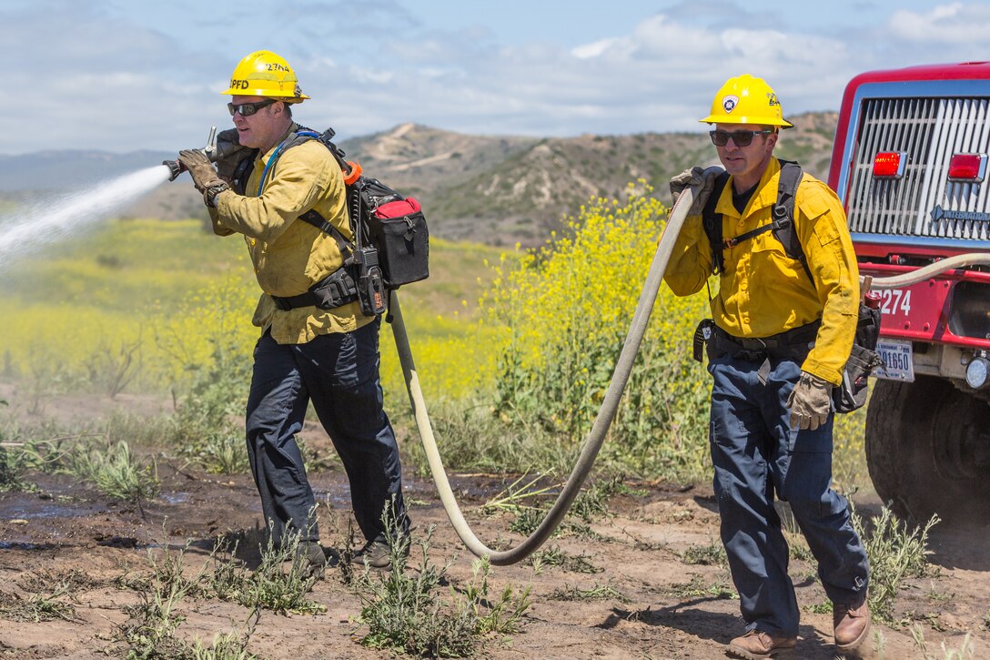 Firefighters with Camp Pendleton Fire Department douse a simulated fire while conducting wild land fire refresher training 130 (WRT) at a mutual threat zone, April 16, 2018. The  annual training, held every spring, revolves around a wildfire scenario that the firefighters must work together to contain. After the drill, participants discussed which elements went well as well as areas for improvement to ensure readiness for the upcoming fire season. (U.S. Marine Corps photo by Lance Cpl. Kerstin Roberts)
