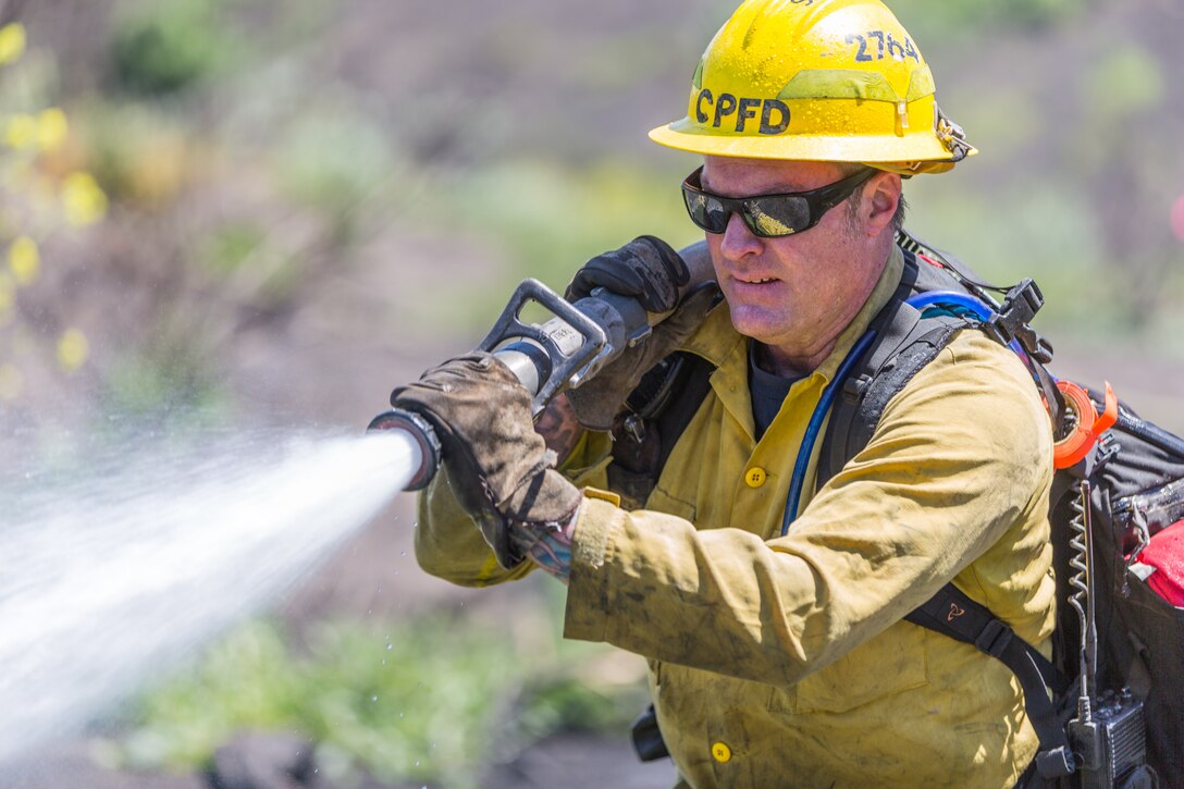 Firefighter Mark Williams, Station 4, Camp Pendleton Fire Department, douse a simulated fire while conducting wild land fire refresher training 130 (WRT) at a mutual threat zone, April 16, 2018. The mandatory annual training, held every spring, revolves around a wildfire scenario that  firefighters must work together to contain. After the drill, participants discussed which elements went well as well as areas for improvement to ensure readiness for the upcoming fire season. (U.S. Marine Corps photo by Lance Cpl. Kerstin Roberts)