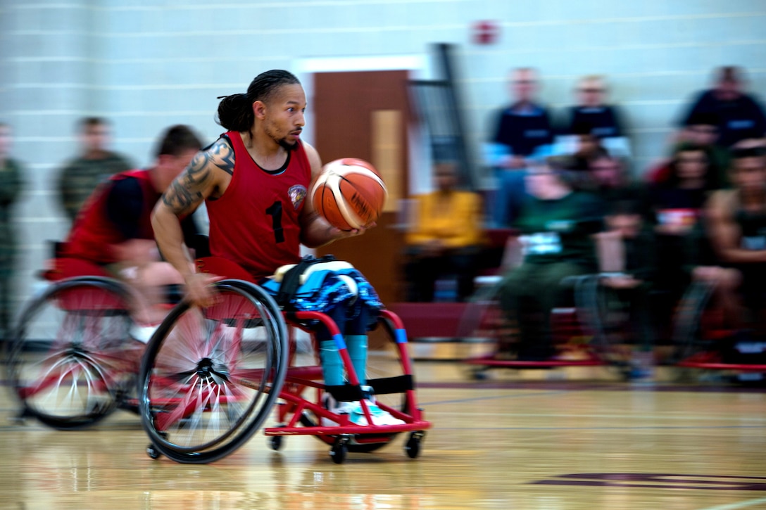 A person in a wheelchair carries a basketball.