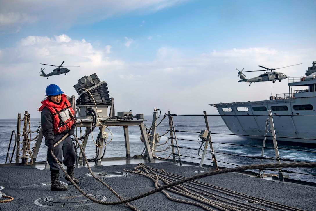 A sailor pull a line aboard a ship.