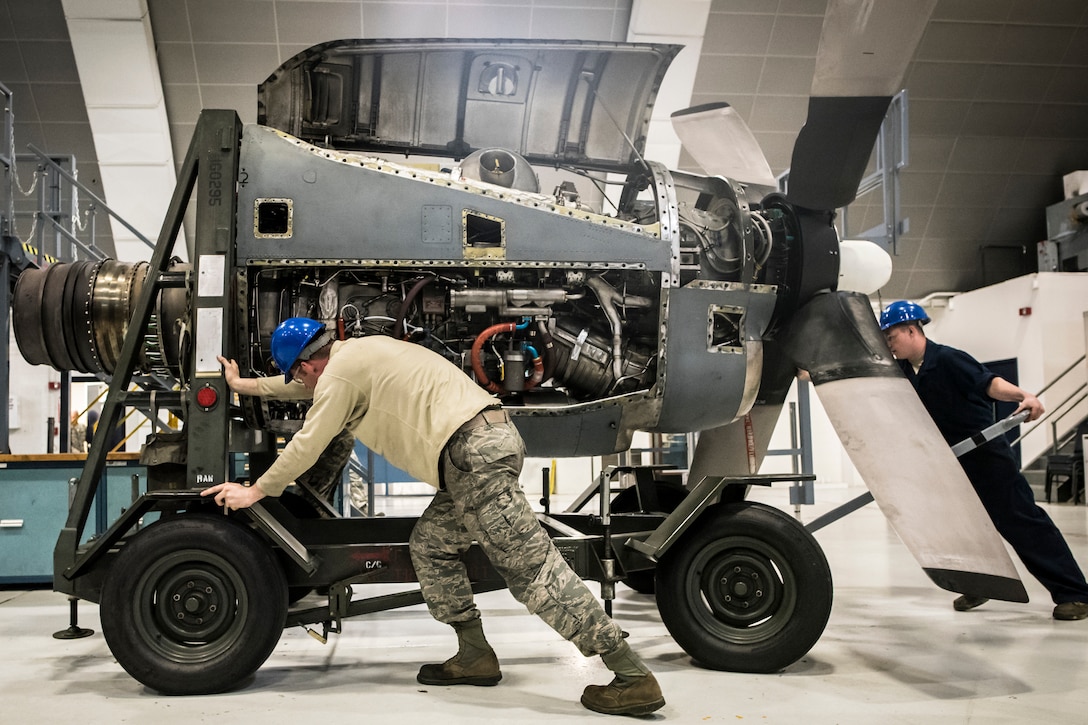 Airmen push an engine into place.