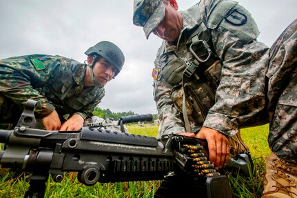 Sgt. 1st Class Harry R. Martinez, right, with the New Jersey Army National Guard, demonstrates how to load an ammunition drum on a M249 squad automatic weapon to Albanian Officer Candidate Endri Deda while training at Joint Base McGuire-Dix-Lakehurst, N.J. The New Jersey National Guard and Albania are paired together as part of the National Guard Bureau's State Partnership Program, which links National Guard elements with partner nations worldwide. The SPP began with three partnerships in 1993 and now, 25 years later, includes 74 partnerships spanning the globe.