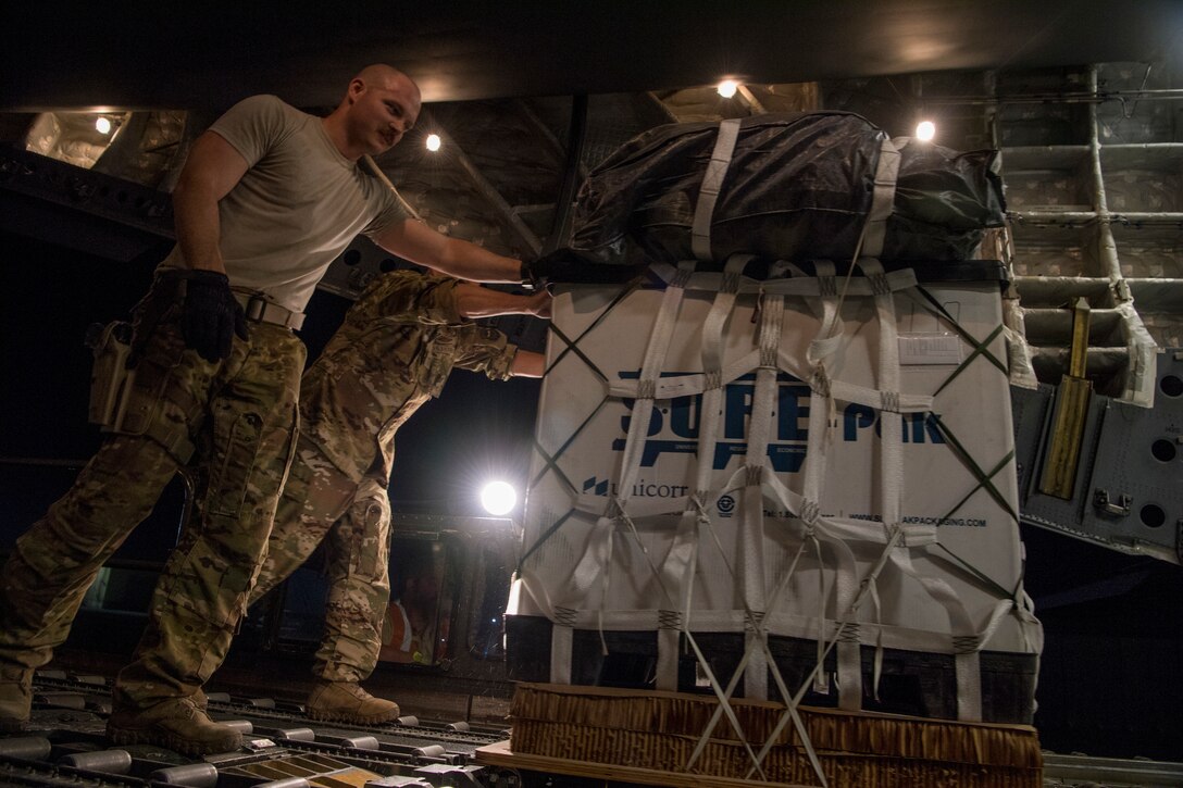 U.S. Air Force Senior Master Sgt. Davin Lammey, 816th Expeditionary Airlift Squadron superintendent and Senior Airman Jeremy Kosick, 816th EAS instructor loadmaster, loads a container delivery system bundle onto a C-17 Globemaster III before a airdrop mission at Bagram Airfield, May 10, 2018. The primary mission of the C-17 is to provide rapid strategic delivery of troops and various types of cargo to bases throughout the U.S. Central Command area of responsibility. (U.S. Air Force photo by Staff Sgt. Keith James)