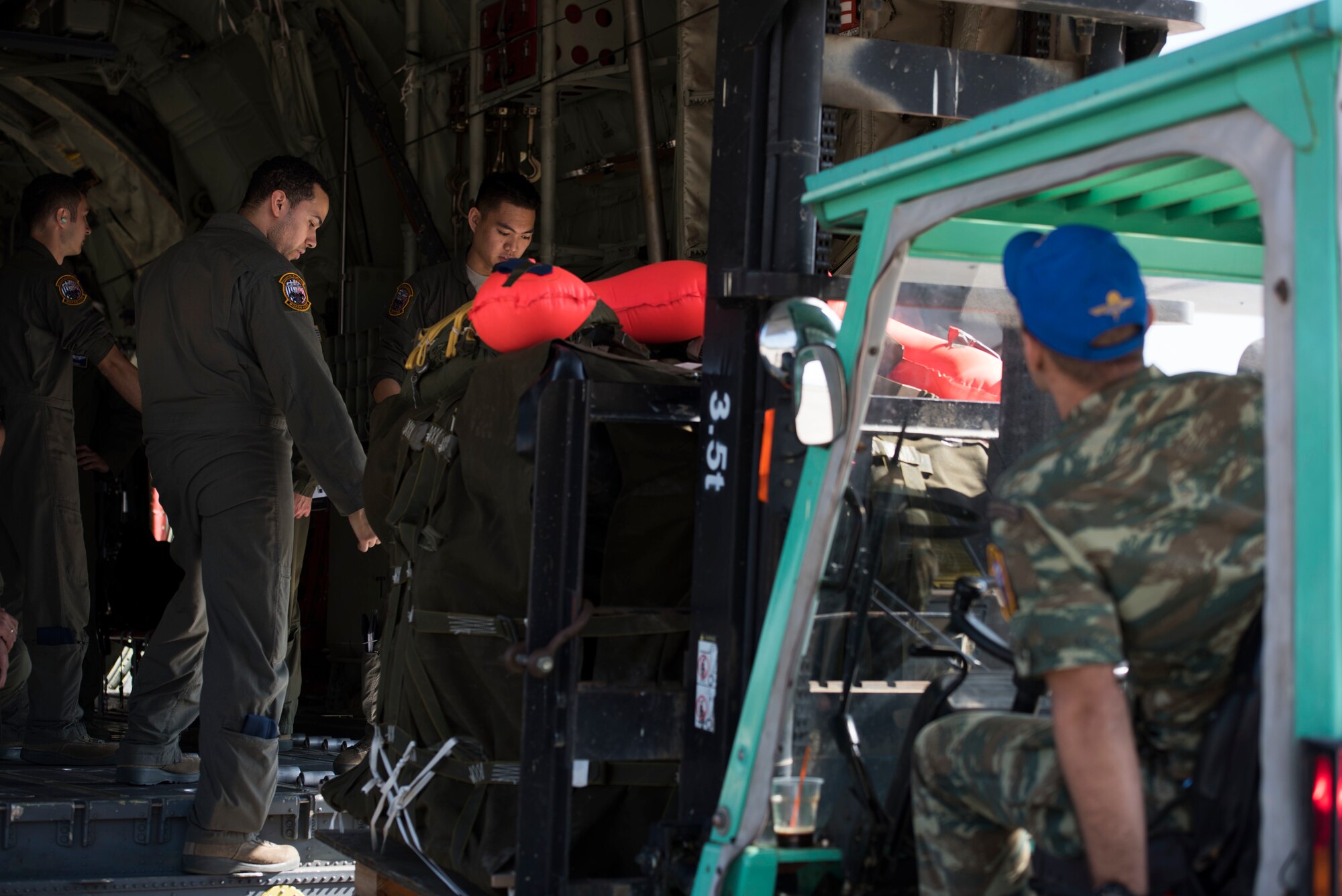 U.S. Air Force Staff Sgt. Jayson Cruz Santiago (left) and Airman 1st Class David Tan, both 37th Airlift Squadron C-130J Super Hercules loadmasters, inspect a rigging alternate method zodiac bundle as a Hellenic air force Airman drives a forklift during exercise Stolen Cerberus V, on Elefsis Air Base, Greece, May 9, 2018. Loadmasters are required to verify cargo is packed properly before allowing the cargo to fly. The United States and Greece, as NATO allies, are continually seeking opportunities to continue developing our strong relationship. (U.S. Air Force photo by Senior Airman Devin M. Rumbaugh)