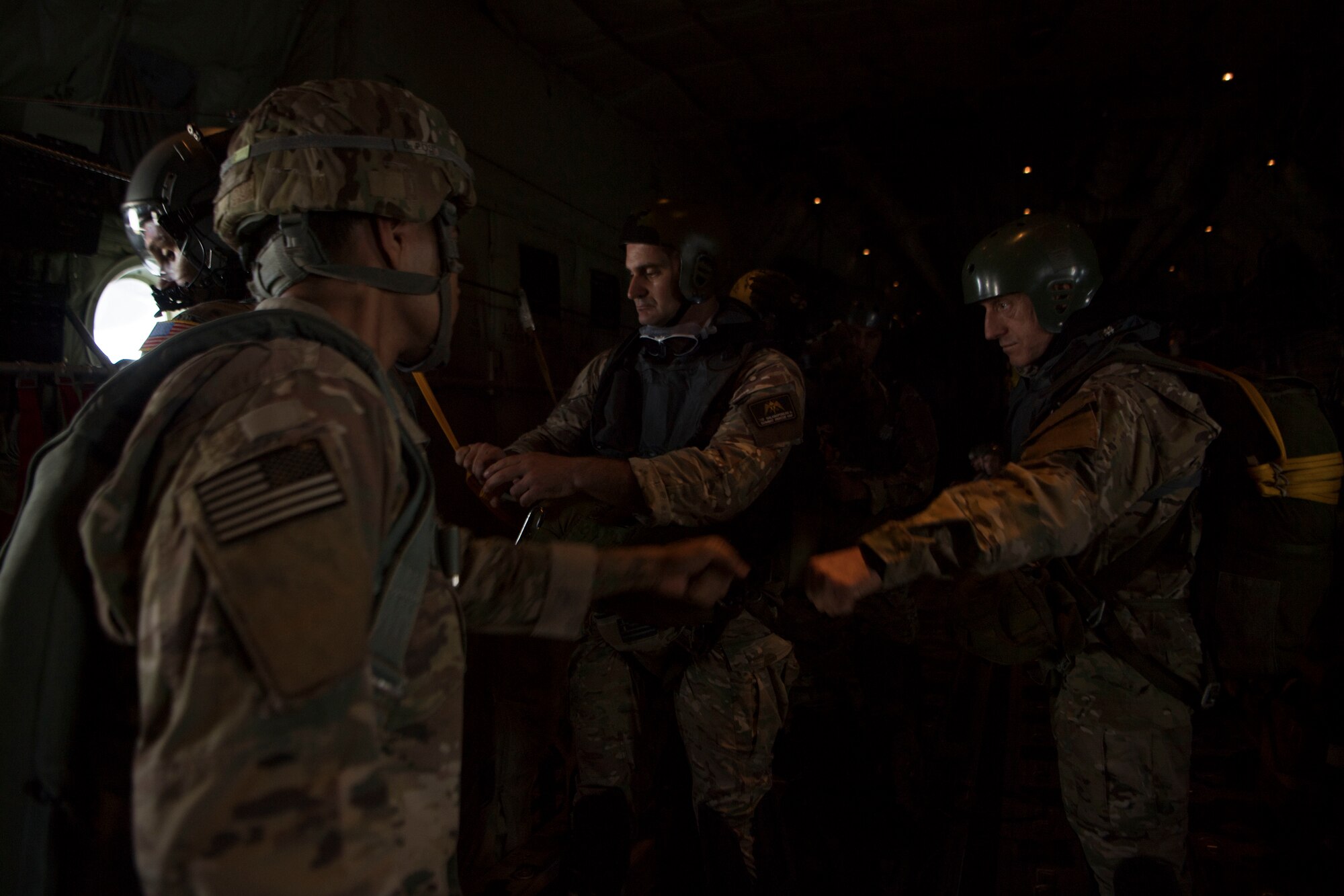 U.S. Army Sgt. Onnie Conyer, 21st Theater Sustainment Command 5th Quartermaster Company jumpmaster, fist bumps a Hellenic paratrooper during an exercise Stolen Cerberus V training mission in the skies near Elefsis Air Base, Greece, May 9, 2018. Jumpmasters are responsible for all parachutes and troopers jumping off the aircraft. (U.S. Air Force photo by Senior Airman Devin M. Rumbaugh)