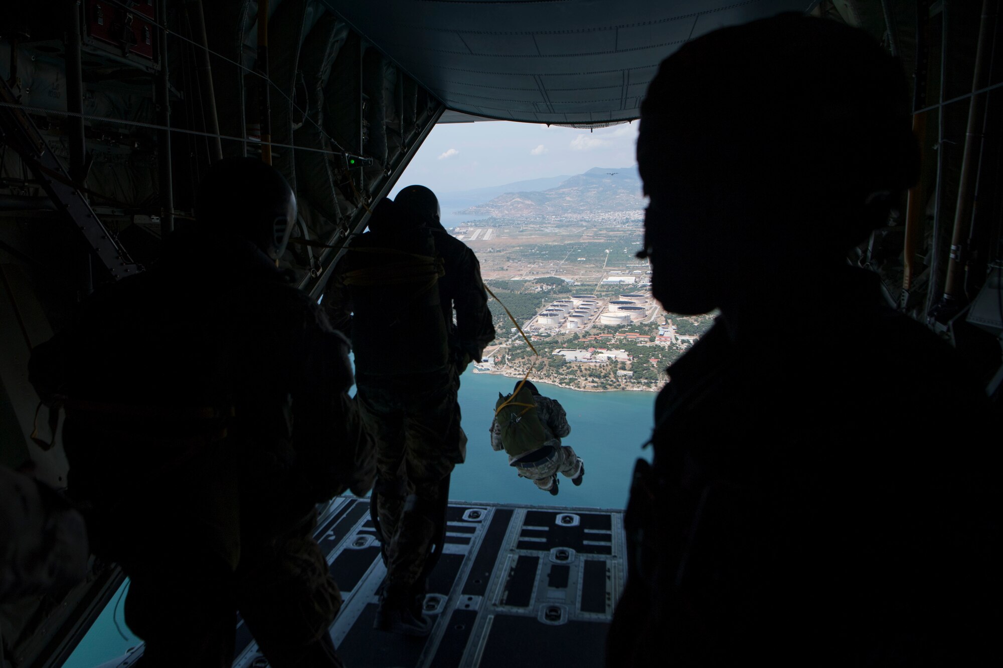 U.S. Army Sgt. Onnie Conyer (right), 21st Theater Sustainment Command 5th Quartermaster Company jumpmaster, watches as Hellenic paratroopers jump out of a U.S. Air Force C-130J Super Hercules during an exercise Stolen Cerberus V training mission in the skies near Elefsis Air Base, Greece, May 9, 2018. Conyer was responsible for verifying all jumpers were prepared for the jump. (U.S. Air Force photo by Senior Airman Devin M. Rumbaugh)