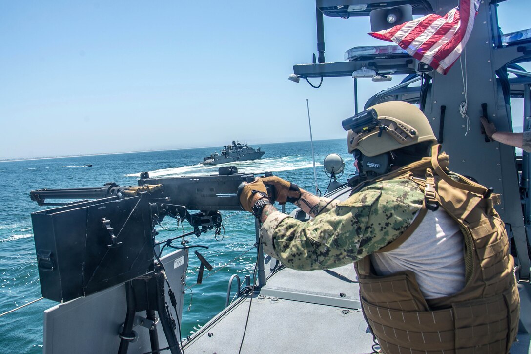 A sailor fires a .50-caliber machine gun.