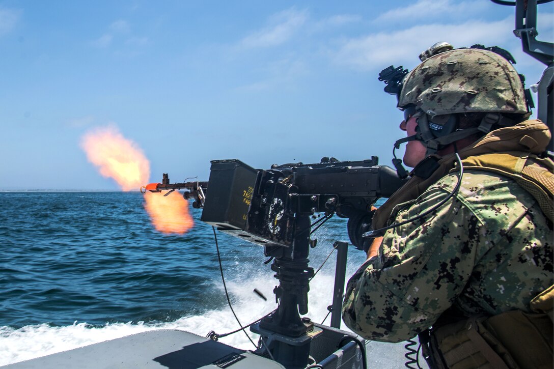 A sailor fires a M240 machine gun.