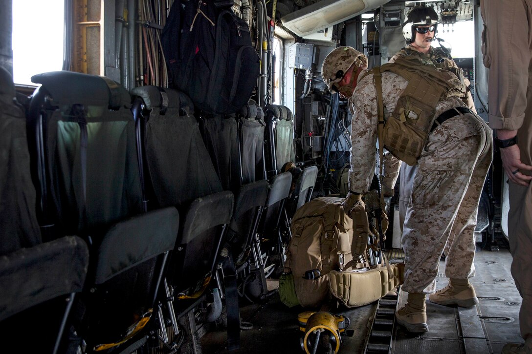 A Marine secures his gear after boarding a helicopter.