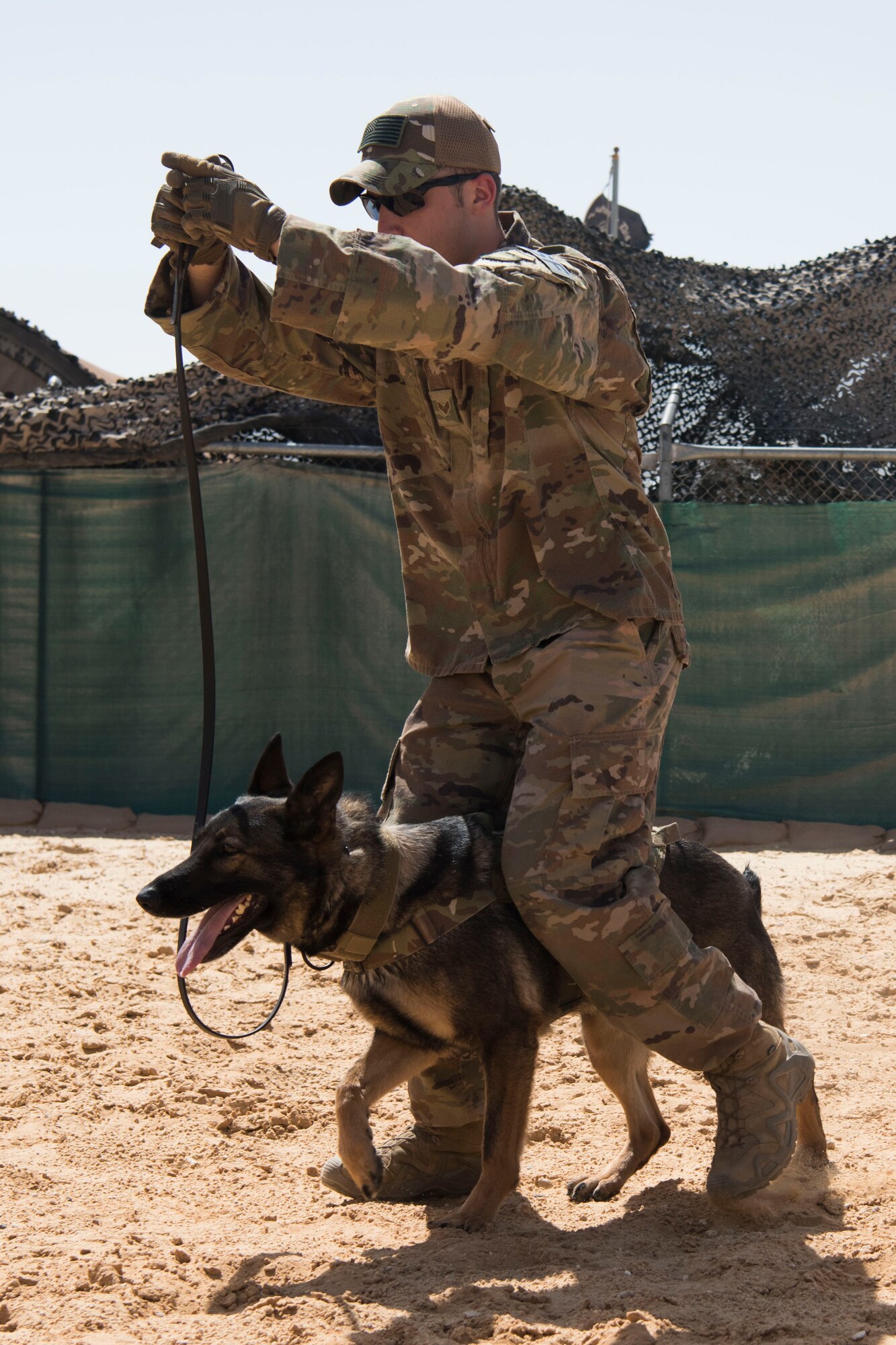 Senior Airman Eliot Tremblay, 332nd Expeditionary Security Forces Squadron military working dog handler, with his MWD partner demonstrates tactical obedience during a military working dog demonstration May 11, 2018, as part of Police Week at an undisclosed location in Southwest Asia.