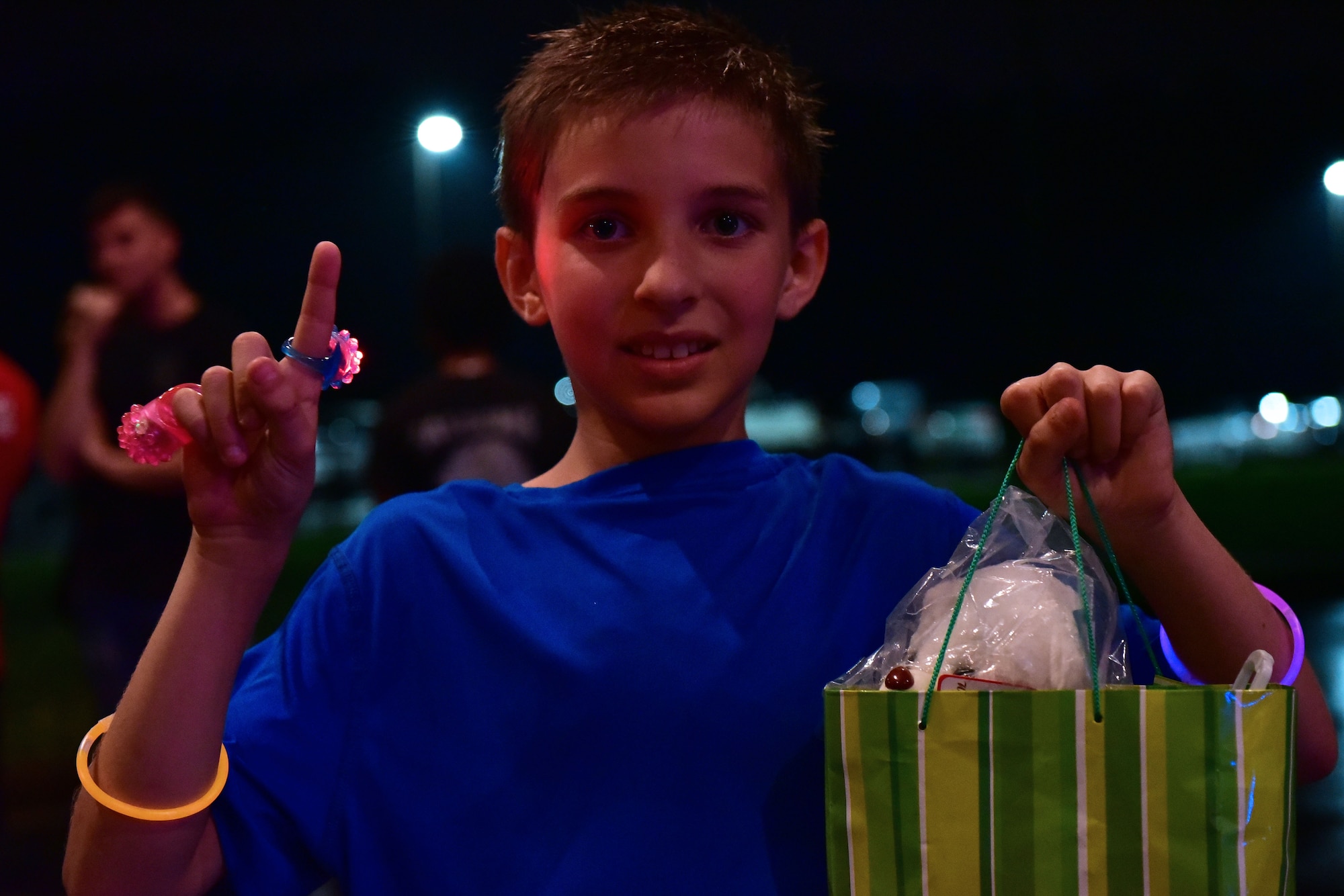 Child holds up index finger and prize bag as he smiles at the camera.