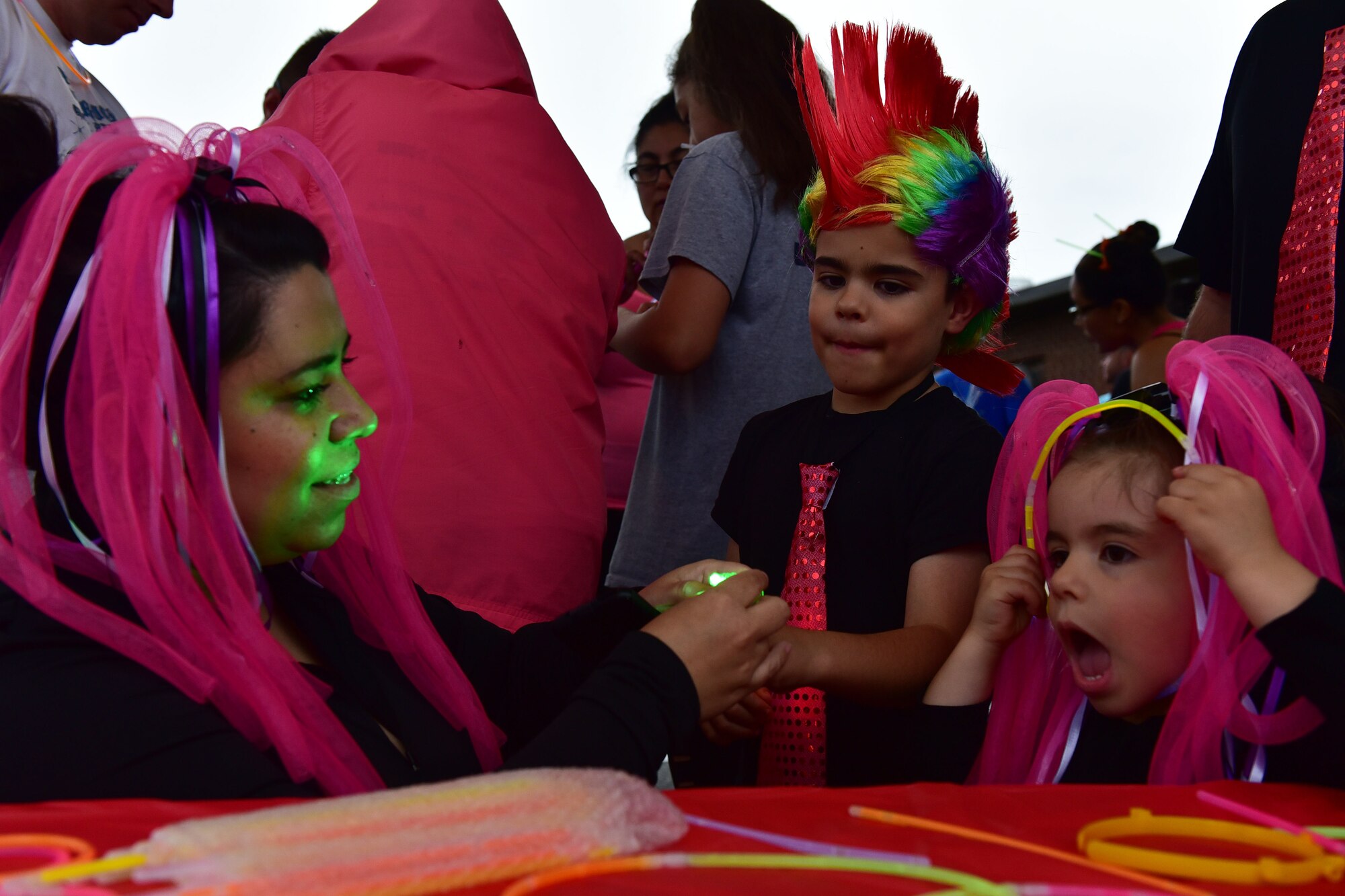 Woman puts glow light on child's finger as little girl puts glow headband on.