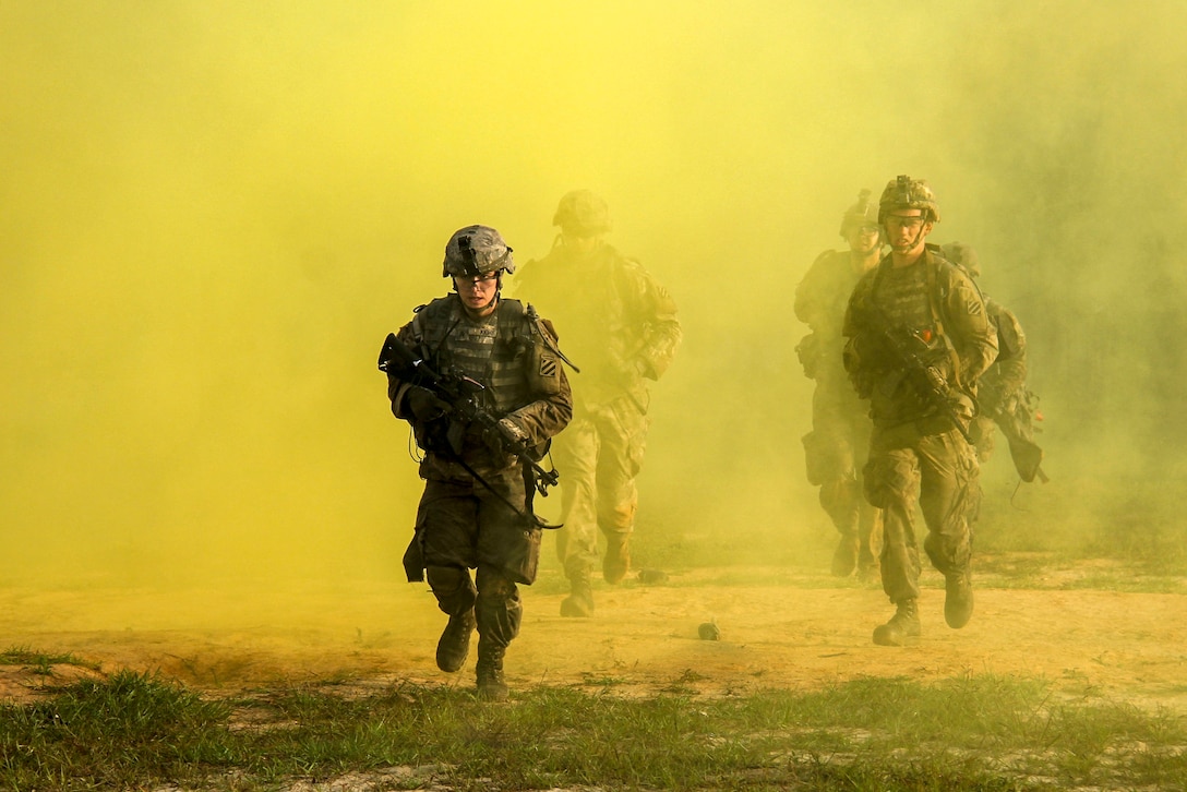 Soldiers move quickly through yellow smoke.