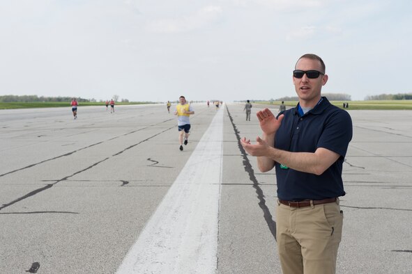 Dustin Fulkerson, 434th Force Support Squadron exercise physiologist, cheers on Airman as they run the runway during a physical fitness test at Grissom Air Reserve base, Ind., May 5, 2018. Fulkerson will teach a class aimed at helping Grissom members improve their running abilities. (U.S. Air Force photo/Staff Sgt. Jami K. Lancette)