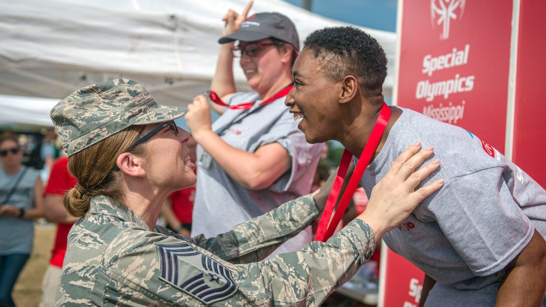 An airman places a medal over the next of an athlete.