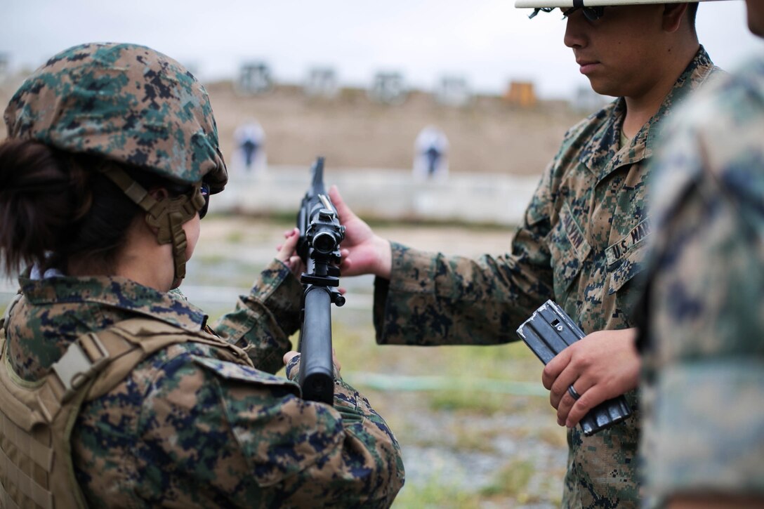 Lance Cpl. Jonathan Galvan, a range coach with Headquarters and Headquarters Squadron, helps a Marine spouse with her shooting technique during “Walk a Mile in Their Boots” at Marine Corps Air Station Miramar, Calif., May 11. “Walk a Mile in Their Boots” is an annual event that gives spouses the opportunity to experience some of the duties and responsibilities of their active duty counterparts. (U.S. Marine Corps photo by Lance Cpl. Mark A. Lowe/Released)