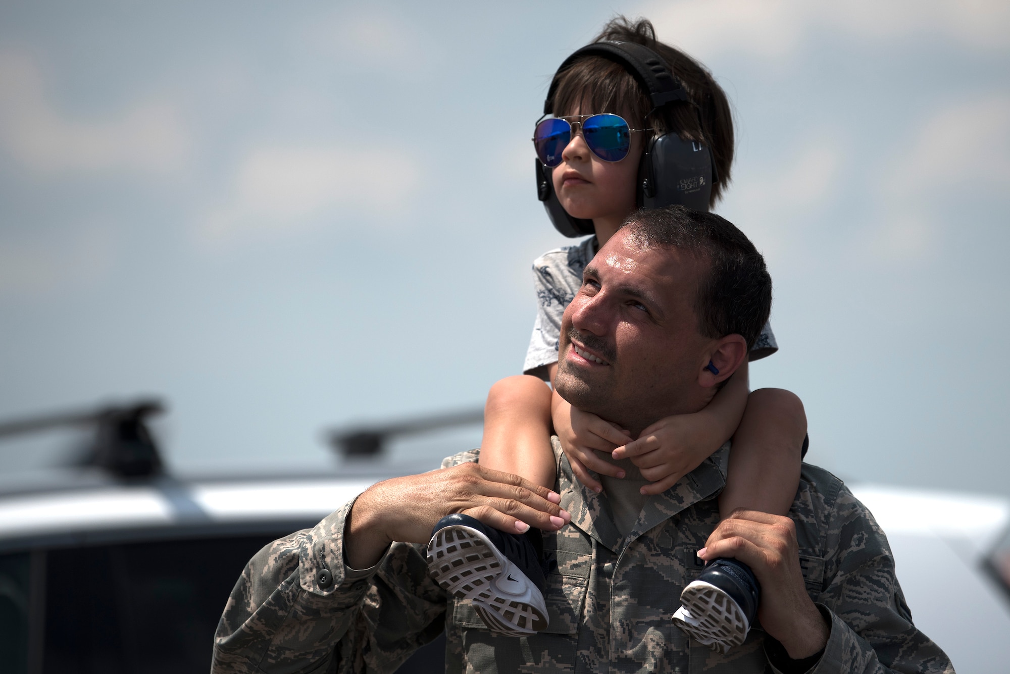 A U.S. Air Force Airman watches aircraft flying by with his son during Tampa Bay AirFest 2018 at MacDill Air Force Base, Fla., May 11, 2018. Over a three-day span, approximately 150,000 attendees experienced aerial demonstrations and interactive static displays.