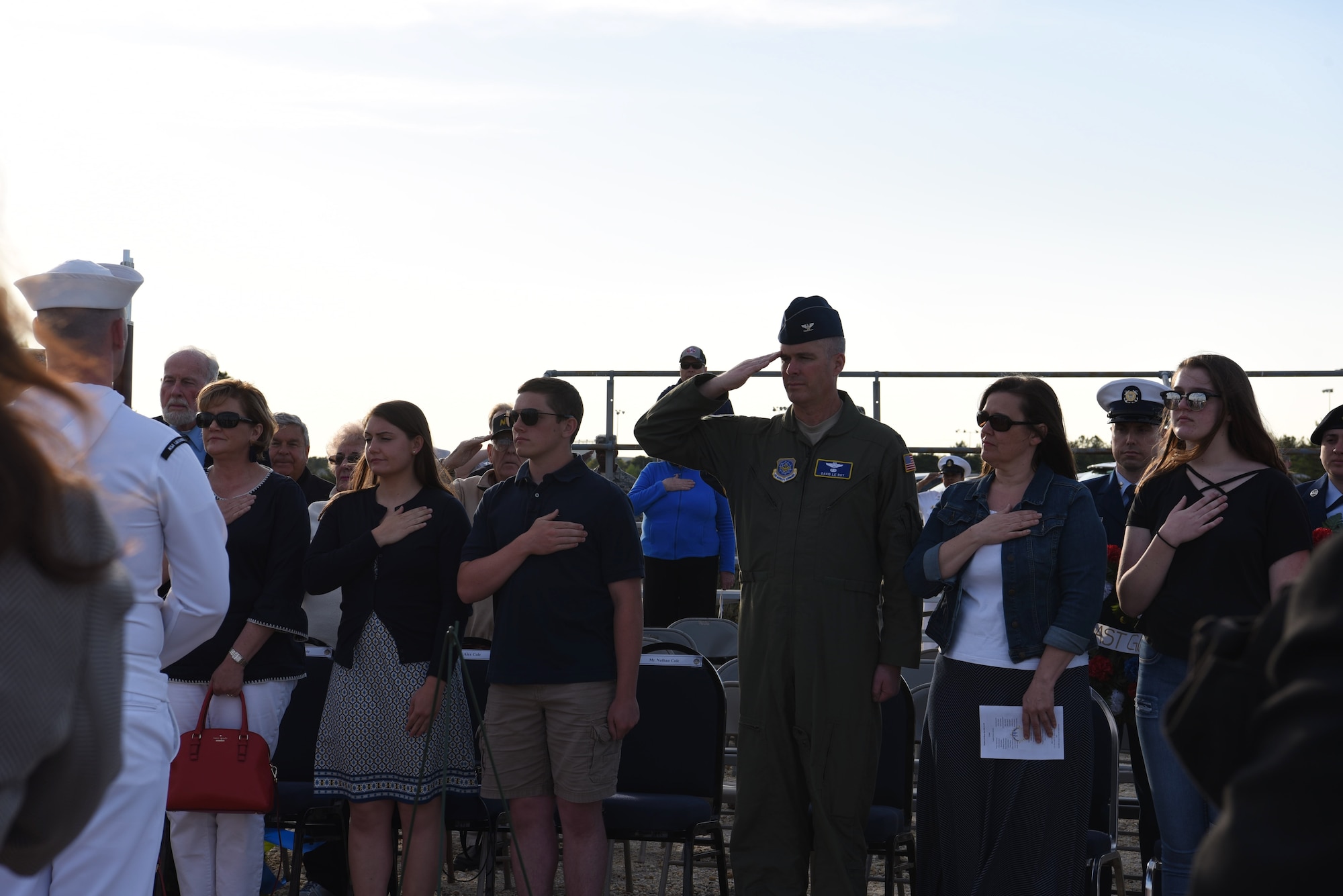 Attendees of the Hindenburg Memorial Ceremony salute or place their hands over their heart during the playing of colors at Joint Base McGuire-Dix-Lakehurst on May 09, 2018. This was the 81st anniversary of the Hindenburg Airship disaster. (U.S. Marine Corps photo by Lance Cpl. Stanley Moy/ Released)