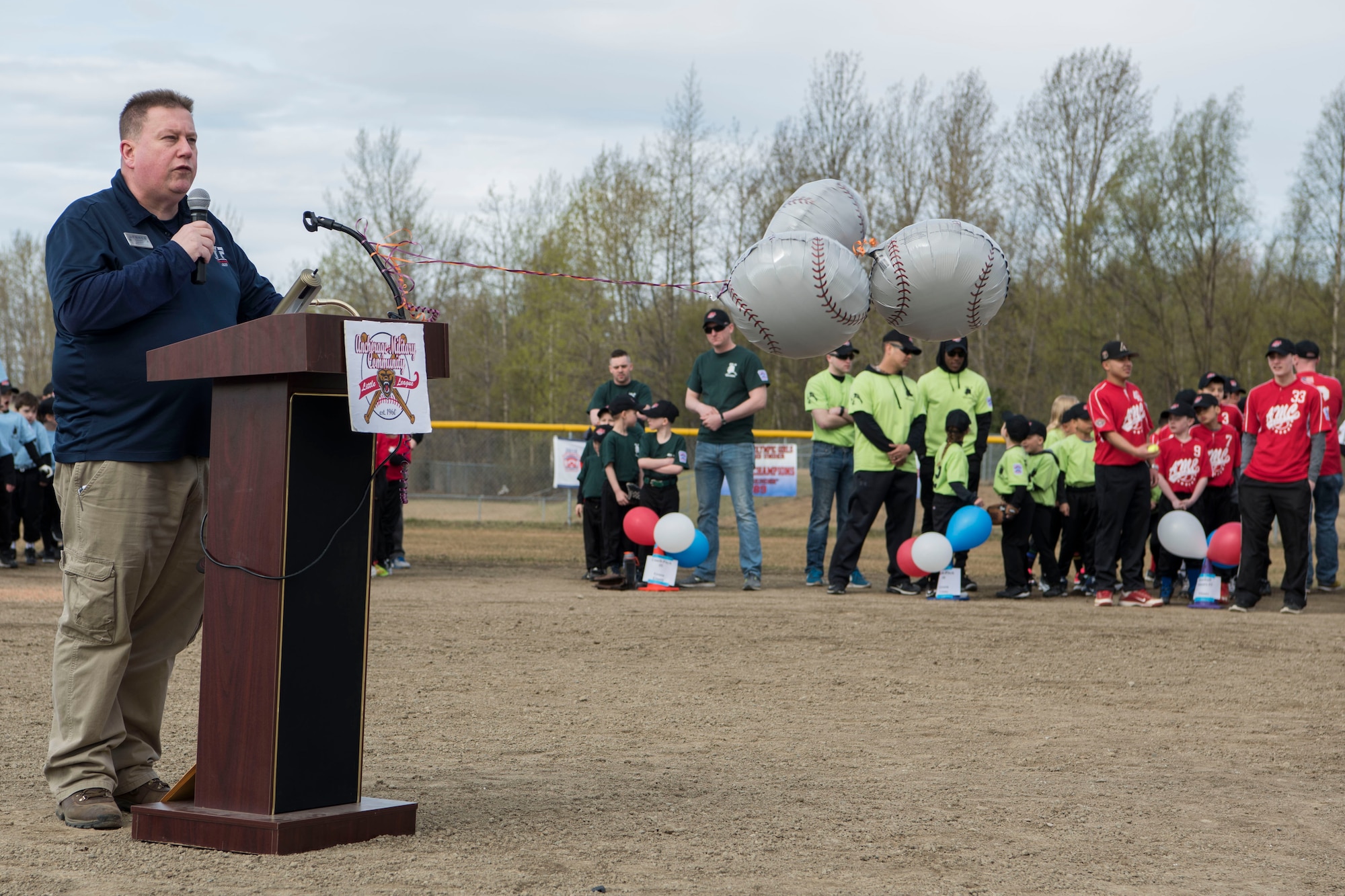 Paul Caron, Joint Base Elmendorf-Richardson Youth Sports director, makes introductions during the Little League opening day ceremony at JBER, Alaska, May 12, 2018. JBER coaches are trained on topics such as the psychology of coaching youth sports, communication, child abuse, injury prevention, and nutrition and hydration, as well as skills and drills.