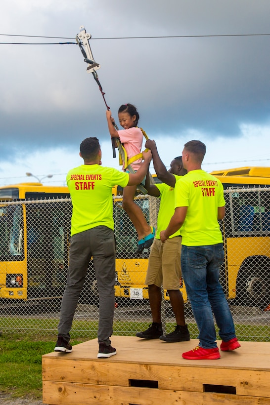 Volunteers help a child down from a zip line during Foster Fest May 12 aboard Camp Foster, Okinawa, Japan. The annual festival allowed members of the community to enjoy food, games and music. More than 13,000 people attended the two-day festival. (U.S. Marine Corps photo by Pfc. Nicole Rogge)