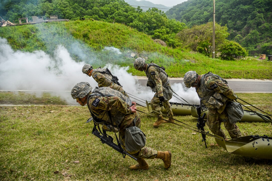 Soldiers run while dragging sleds.