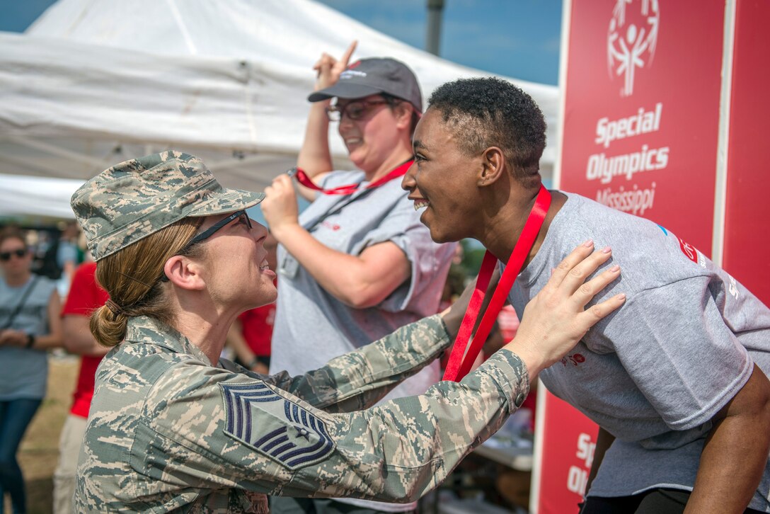 An airman places a medal over the next of an athlete.