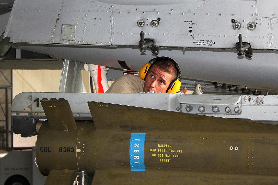 An airman practices loading ordnance onto an aircraft.