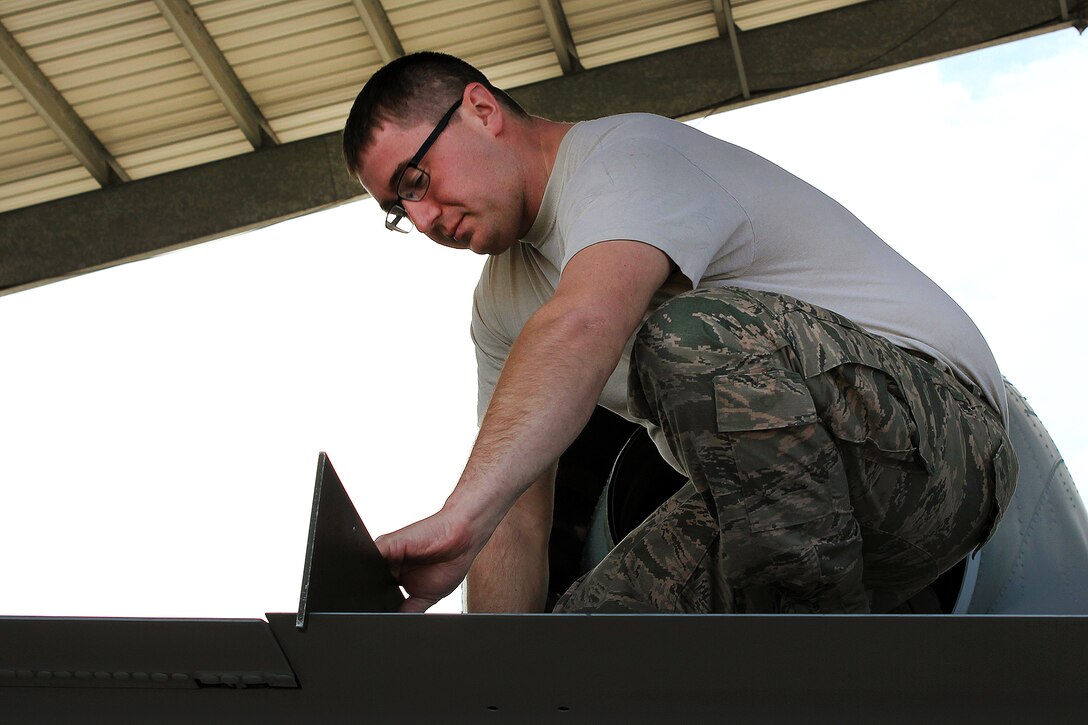 An airman uses a guide to ensure components are correctly aligned.