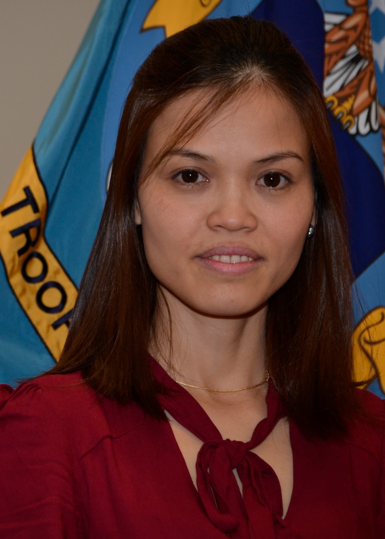 DLA Troop Support student trainee Hue T. Nguyen poses in front of the Troop Support flag following an interview in Philadelphia on April 30.