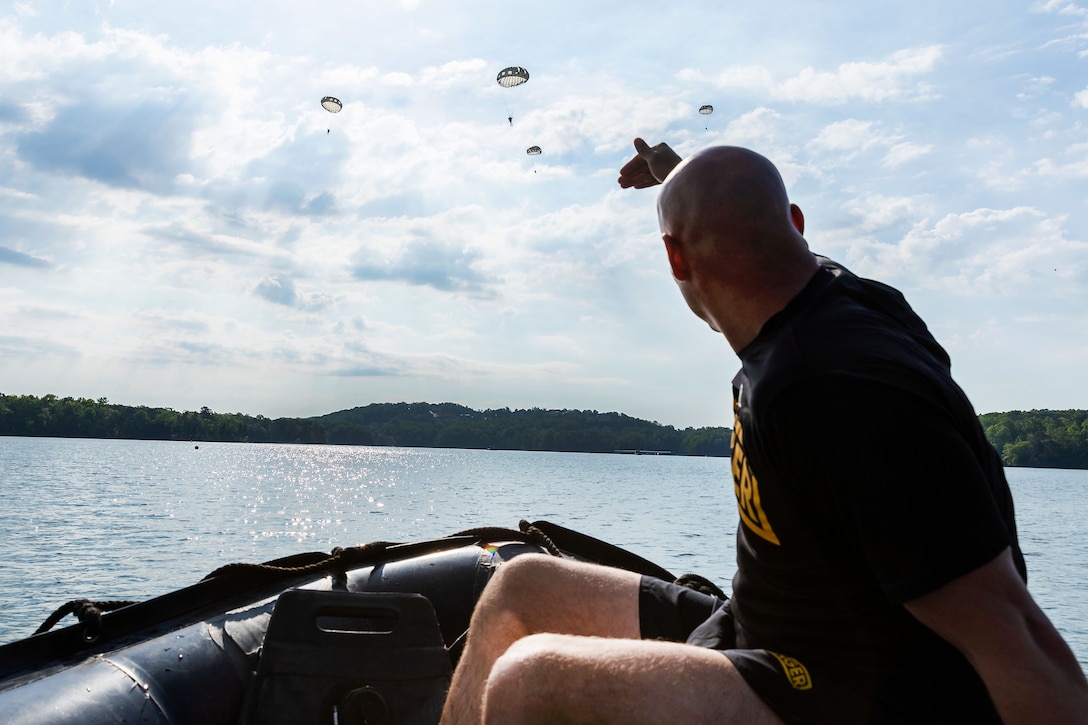 A soldier observes paratroopers conducting airborne operations.