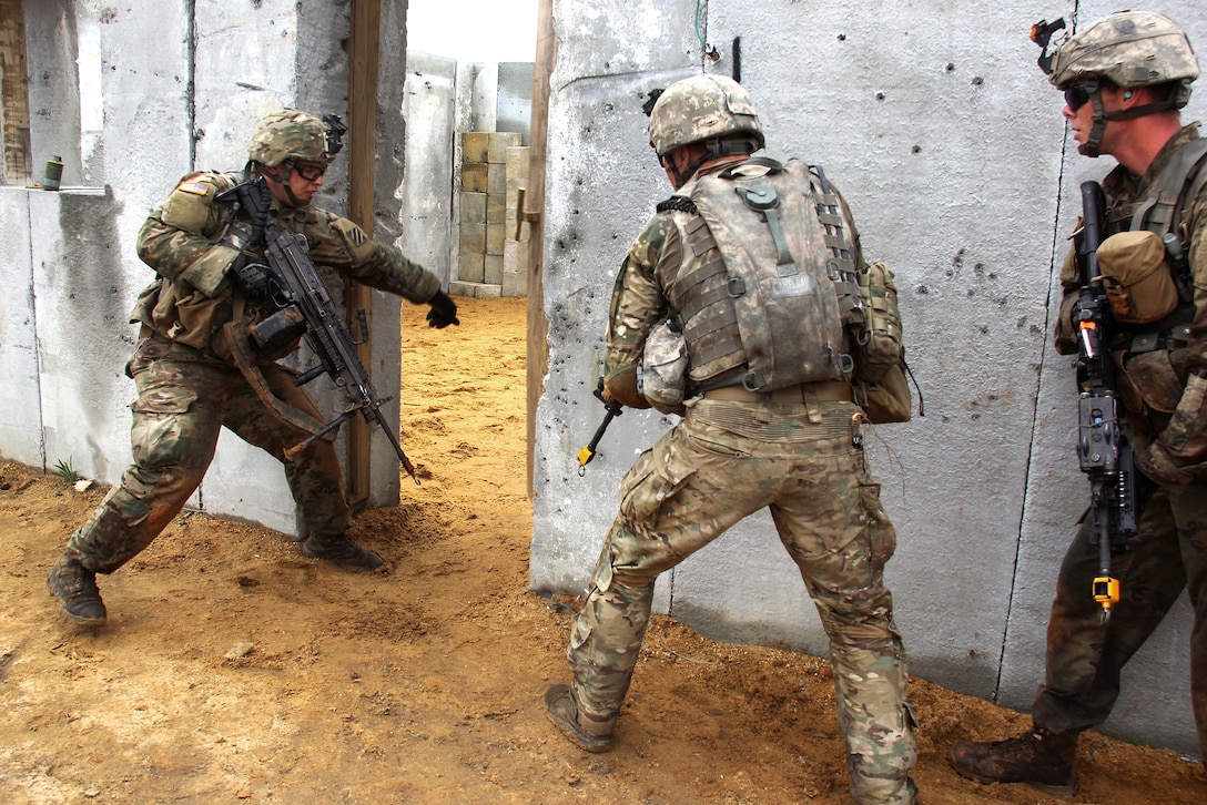 A soldier directs his team to enter and search a building.