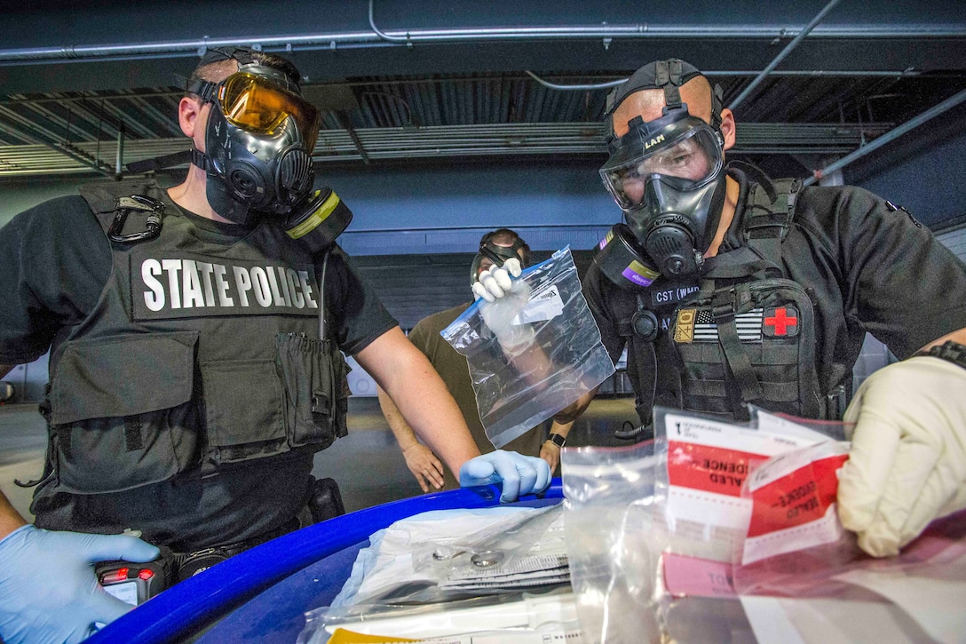 A soldier, police officer prepare evidence bags.
