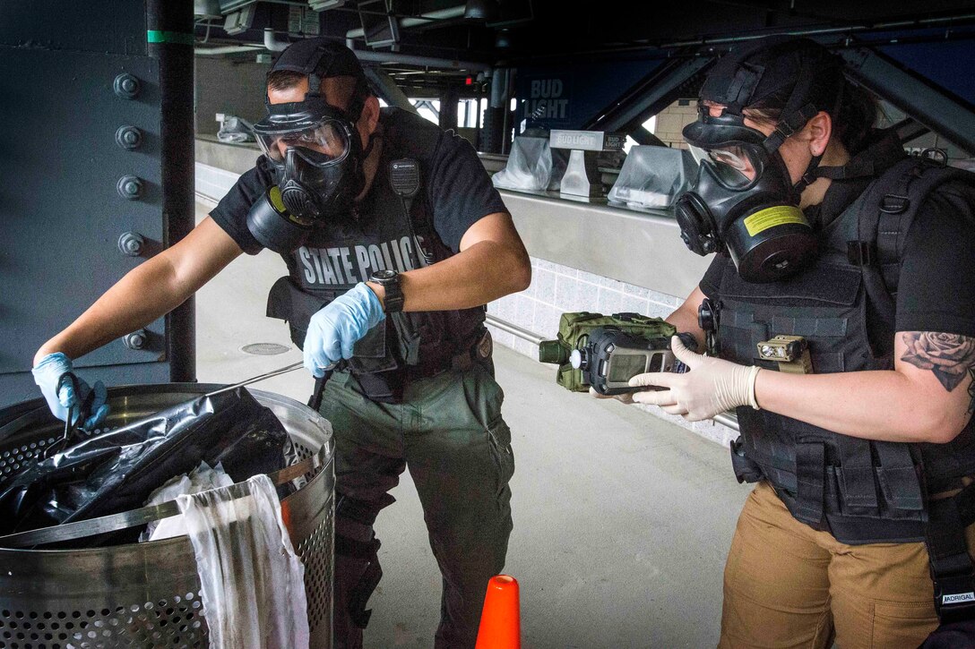 A soldier, police officer open a simulated weapons of mass destruction device.