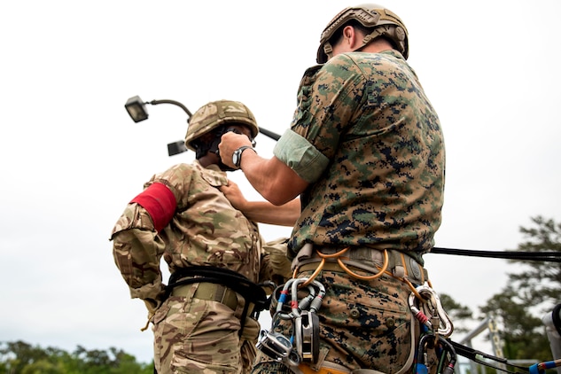 A soldier with the Royal Bermuda Regiment is instructed on rappelling by Staff Sgt. Adam Powell, reconnaissance man, 2nd Reconnaissance Battalion, 2nd Marine Division, at Stone Bay on Marine Corps Camp Lejeune on May 8, 2018. The regiment was at MCB Camp Lejeune for a two week evolution, the Junior Noncommissioned Officer Cadre, which is a course for promotion for the Soldiers in the regiment and is open to all Soldiers who have completed one year of service and have the recommendation of their company commander. (U.S. Marine Corps photo by Sgt. Melodie Snarr)