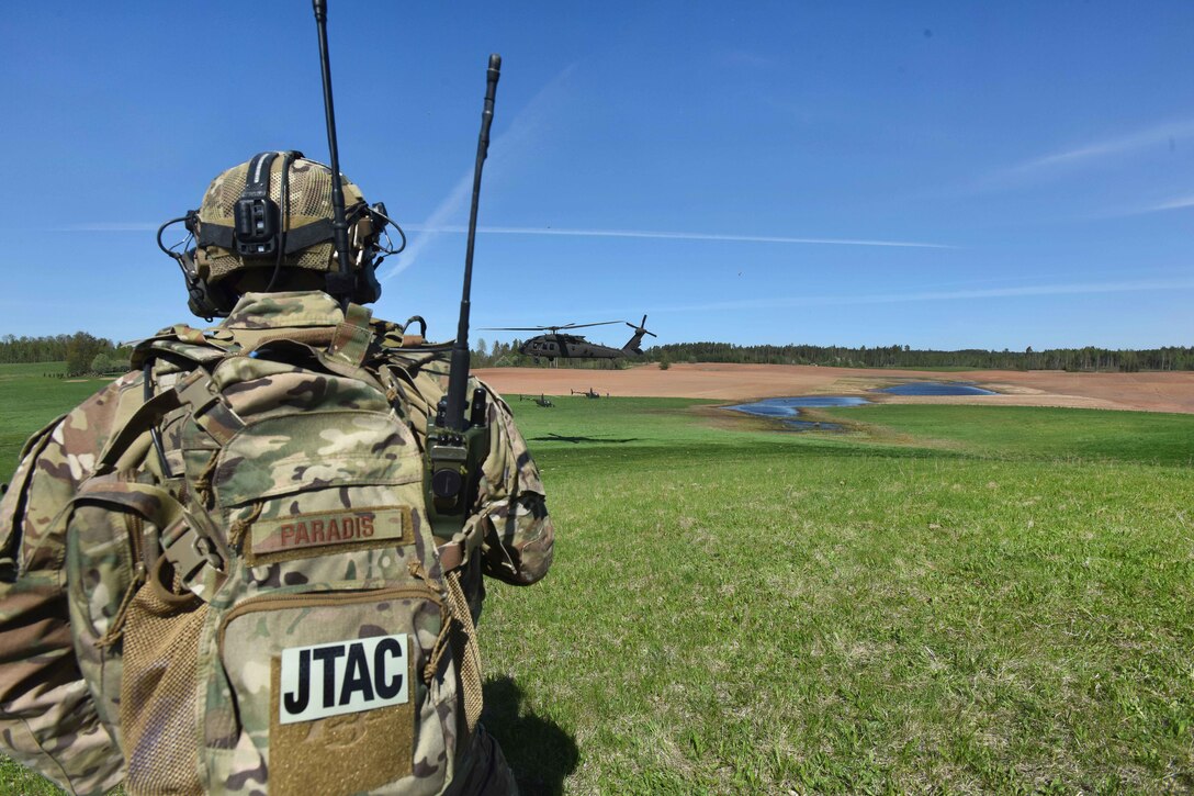 An airman observes as UH-60 Black Hawk helicopter prepare to land.