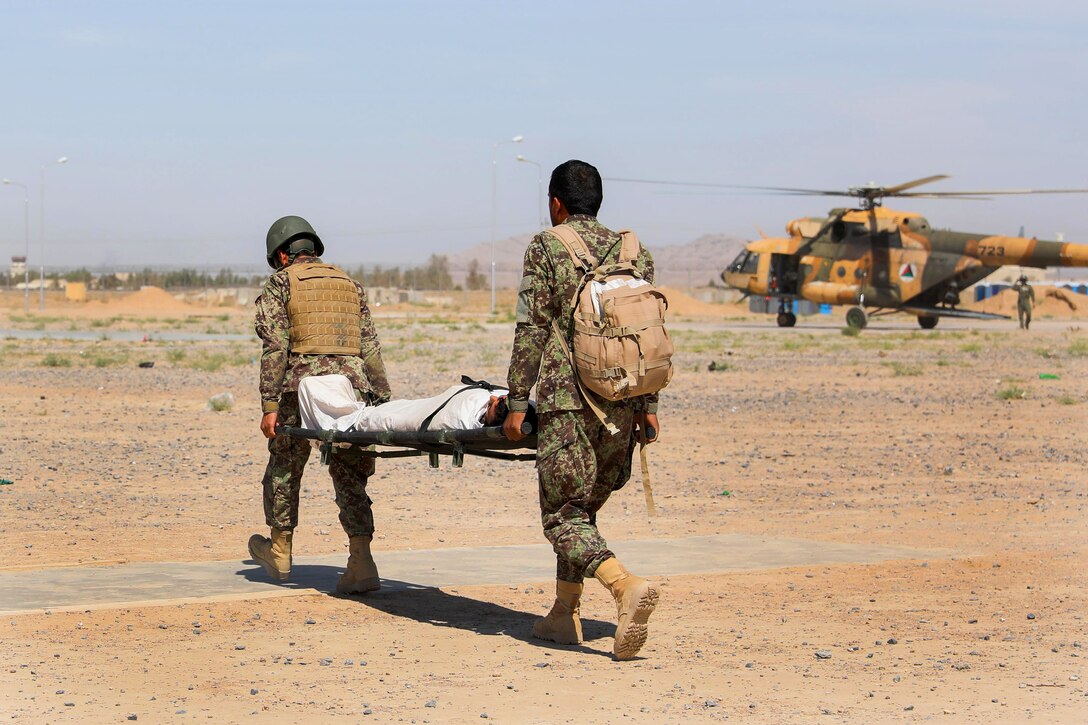Two Afghan soldiers carry a role-playing casualty on a stretcher.