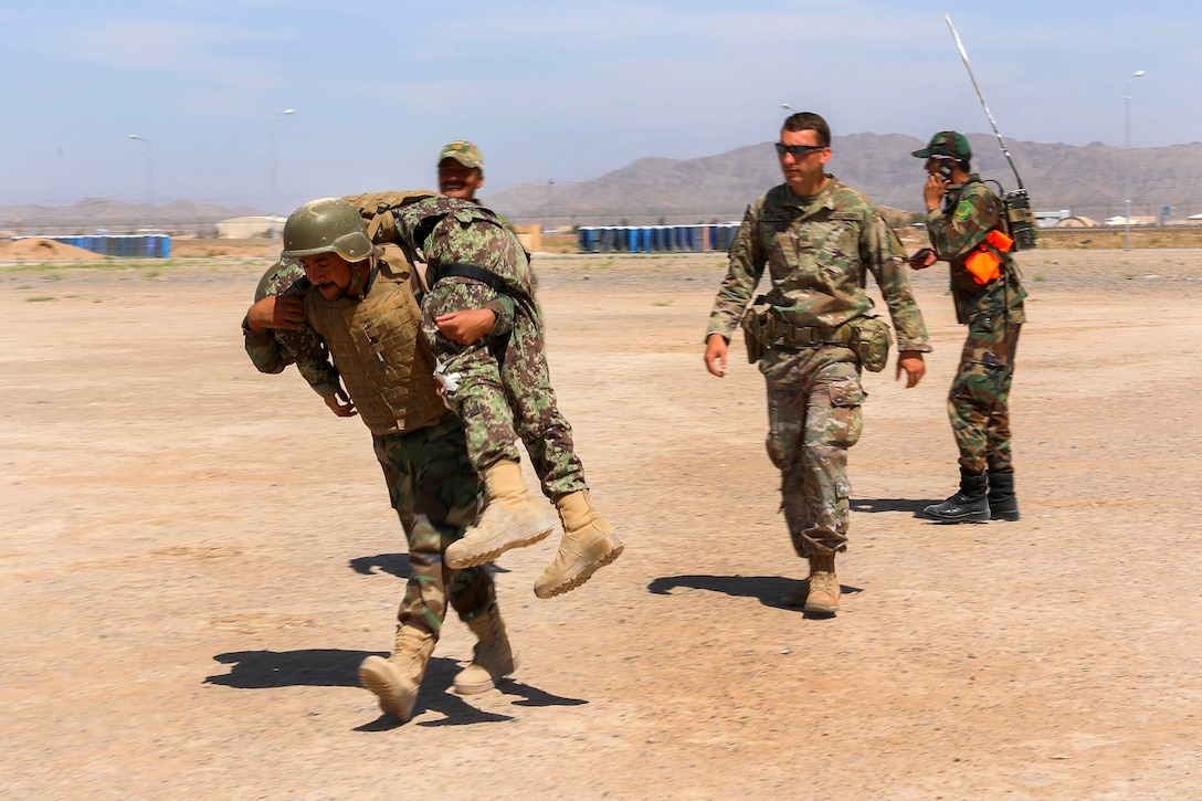 A U.S. soldier watches as an Afghan soldier carries a role-playing casualty.