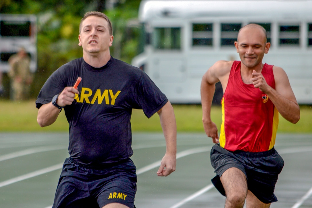 A U.S. and a Singaporean soldier run on a track.