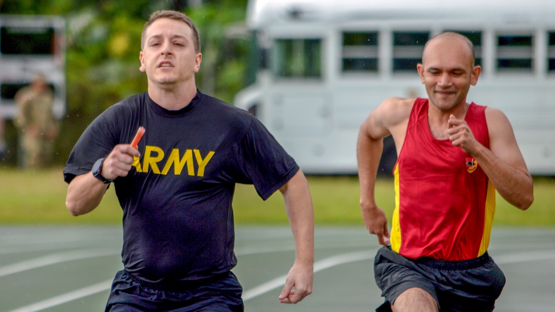 A U.S. and a Singaporean soldier run on a track.