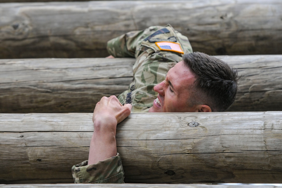 A soldier holds himself up on an obstacle course.