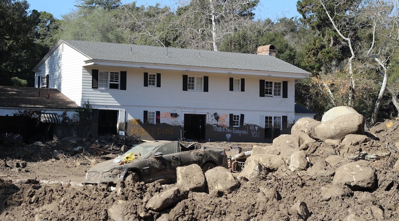A house is seen caked inside and out with mud, while a destroyed vehicle and a pile of debris sits in the front yard following a Jan. 9 mudslide in Montecito, California, a community within Santa Barbara County.