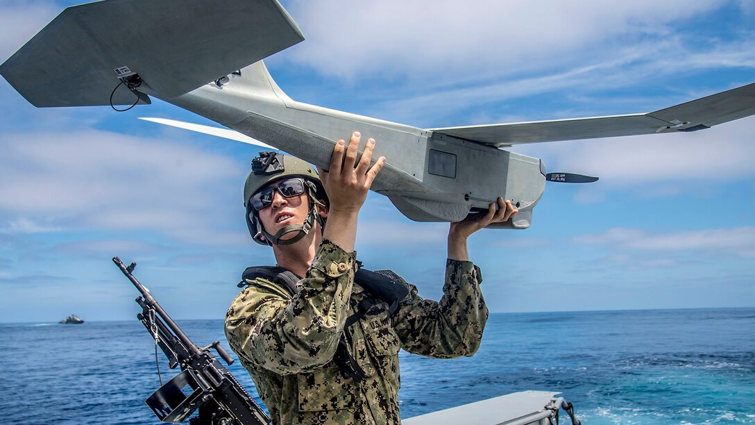 A sailor holds a small aircraft.