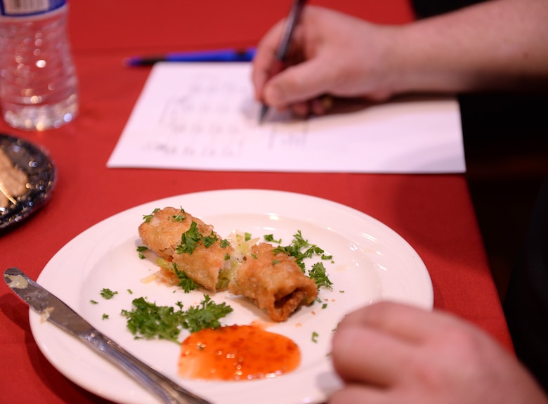A judge writes down his score after tasting an appetizer during the Taste of Luke cooking competition at Luke Air Force Base, Ariz., May 9, 2018. Food was judged based on criteria such as presentation, flavor, and incorporation of special ingredients. (U.S. Air Force photo by Senior Airman Ridge Shan)