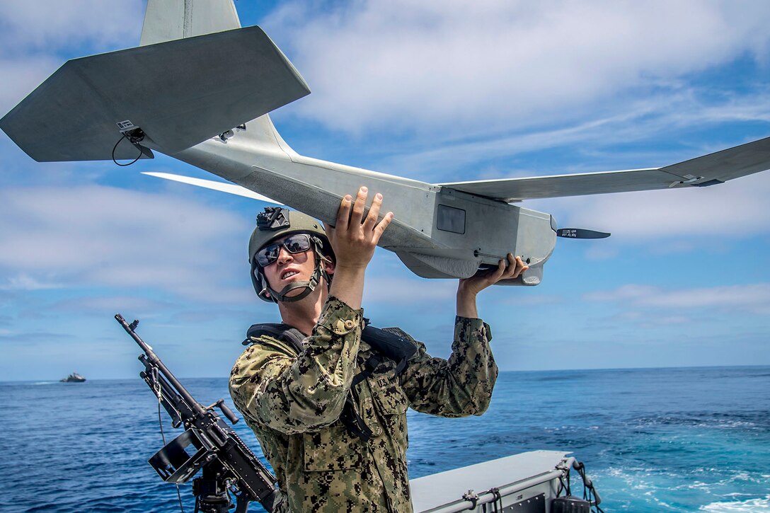 A sailor holds a small aircraft.